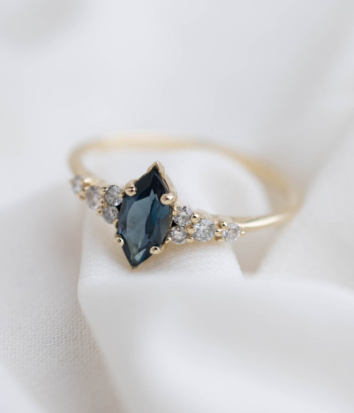 טבעת זהב 14 קראט בעיצוב מלכותי עם אבן חן בצורת מרקיזה במרכז ושיבוץ יהלומים טבעיים משני הצדדים