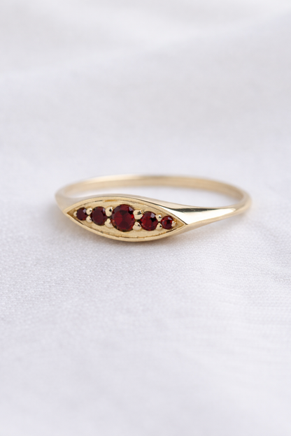 טבעת זהב 14K אובלית מוגבהת, משובצת אבני חן גרנט בשלושה גדלים שונים בעיצוב קלאסי ויוקרתי.