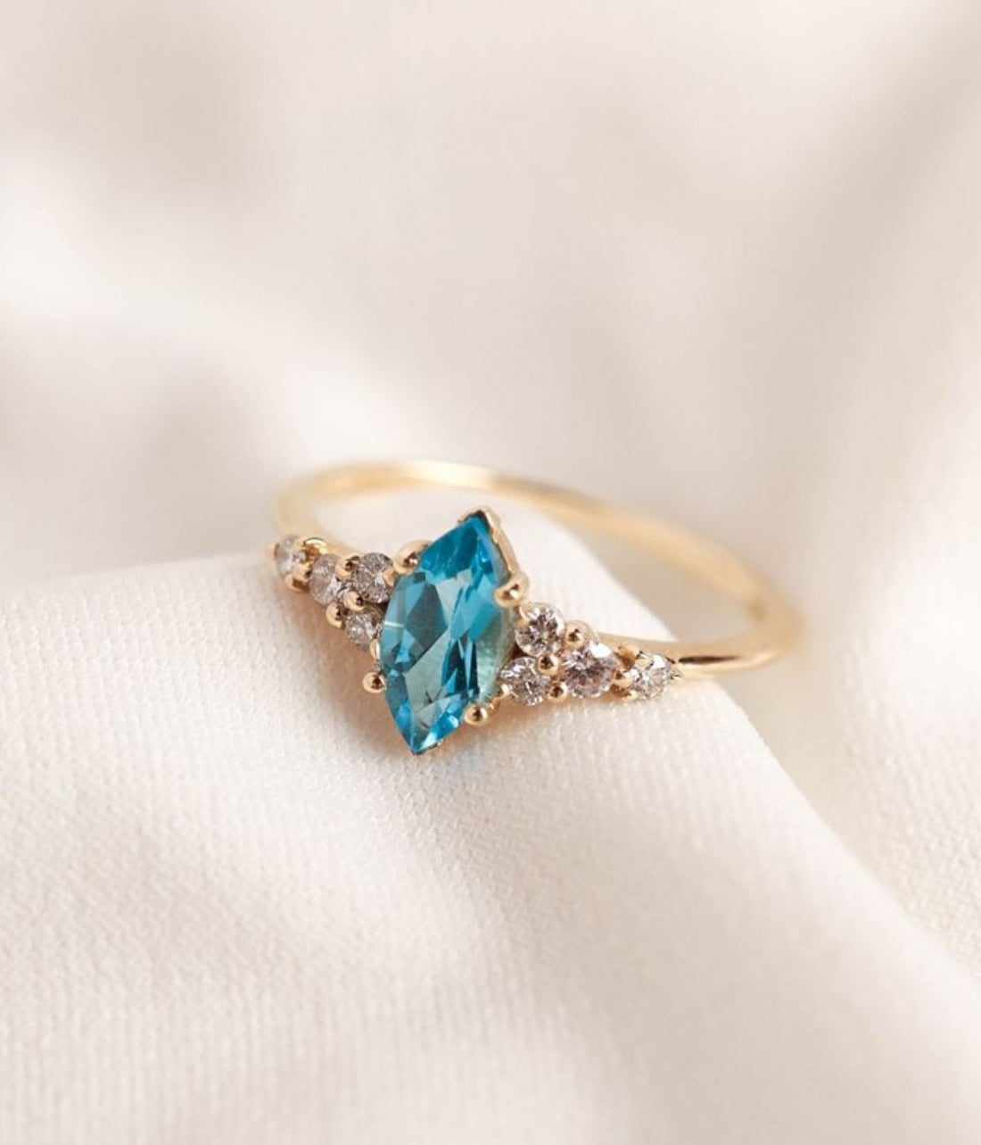 טבעת זהב 14 קראט בעיצוב מלכותי עם אבן חן בצורת מרקיזה במרכז ושיבוץ יהלומים טבעיים משני הצדדים