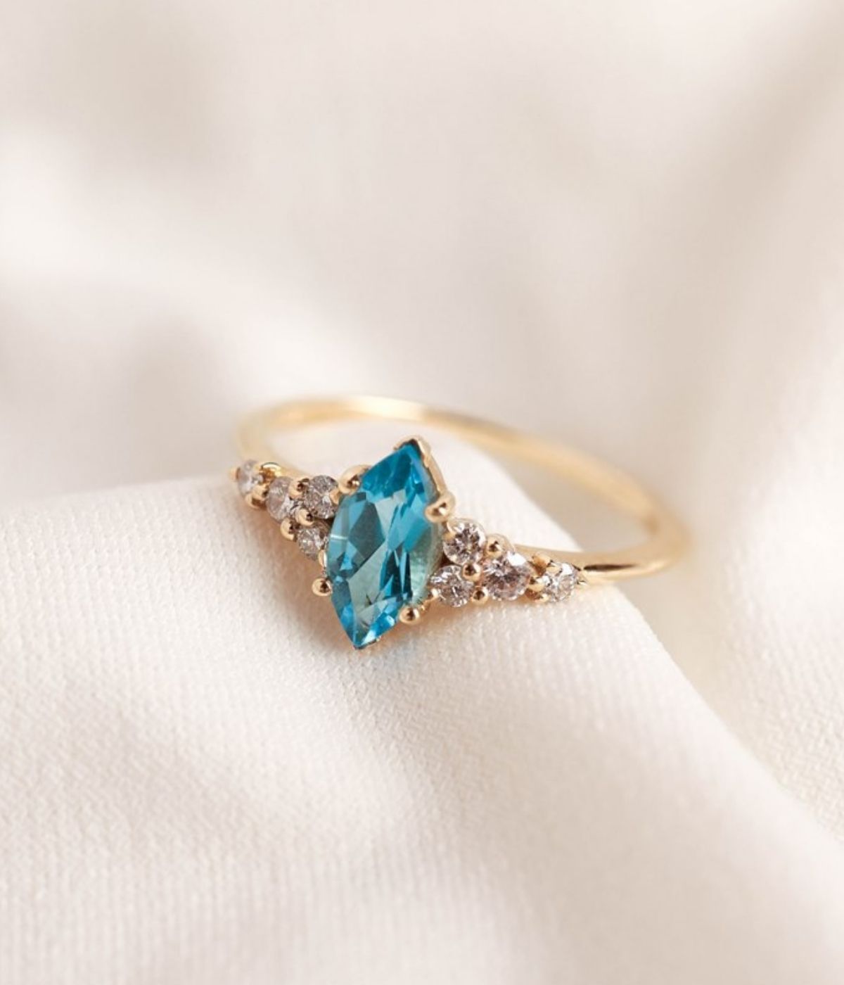 טבעת זהב 14 קראט בעיצוב מלכותי עם אבן חן בצורת מרקיזה במרכז ושיבוץ יהלומים טבעיים משני הצדדים