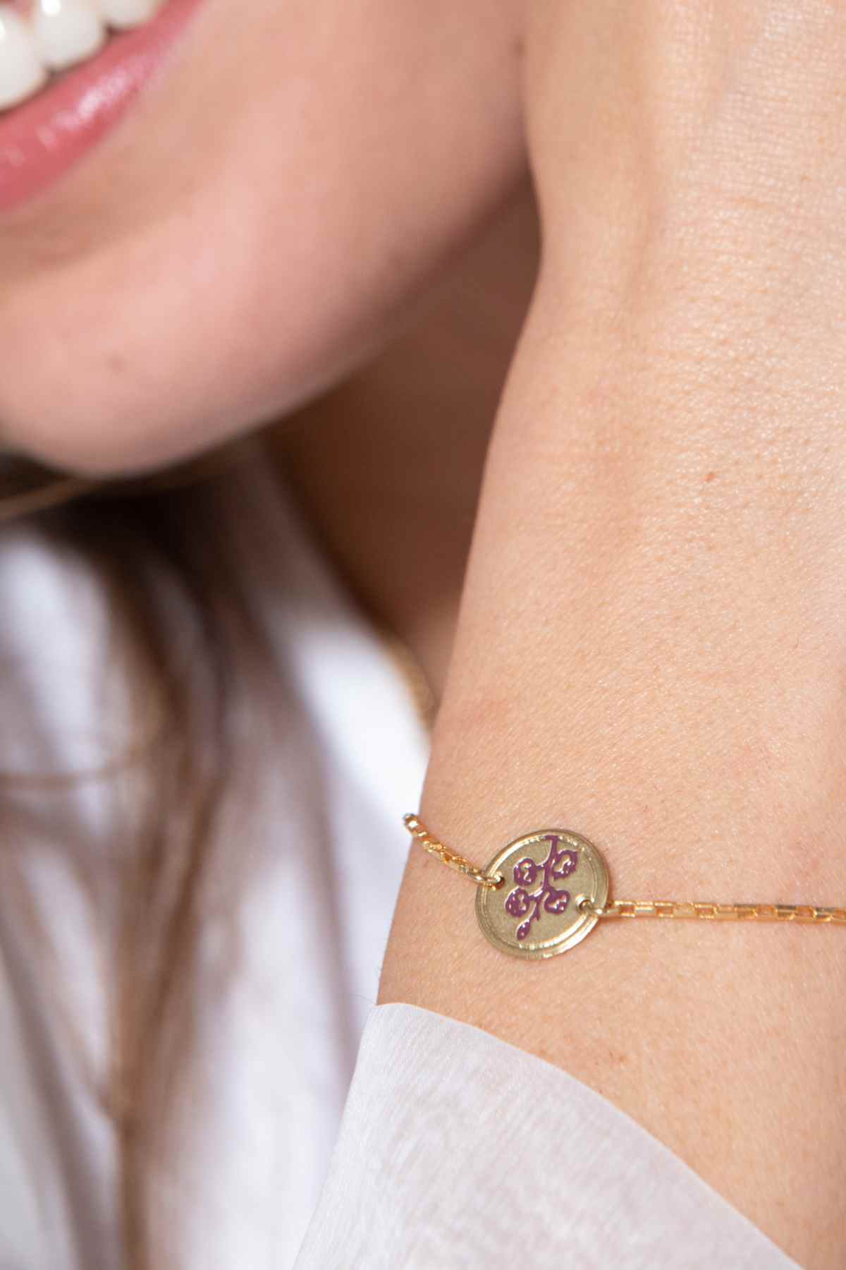 צמיד עיגול כותנה סגול ‘הכל אפשרי’ של הדס קוקה תכשיטים על פרק יד של אישה, עם מדליון זהב ועדין בעבודת יד