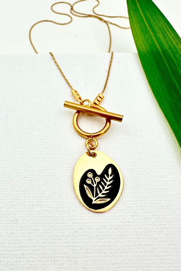 שרשרת דו צדדית שחורה עם סוגר קדמי ותליון אובל א־סימטרי, חריטה של פריחה בצד אחד ושמש וירח בצד השני