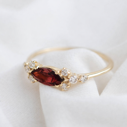 טבעת זהב 14K בעיצוב מלכותי ועדין, עם אבן חן מרכזית בחיתוך מרקיזה מוקפת יהלומים טבעיים, מראה רומנטי ואלגנטי.