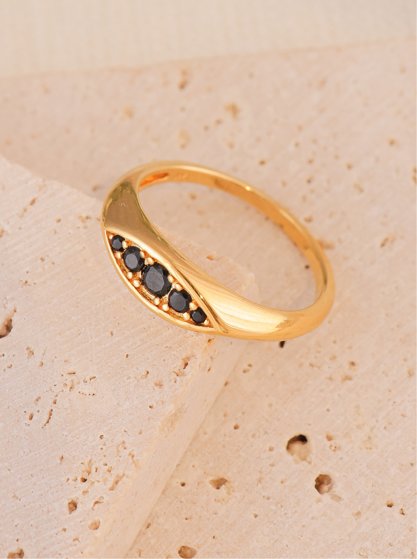 "טבעת ליאן של הדס קוקה – טבעת ציפוי זהב בעיצוב עכשווי עם זרקונים שחורים נוצצים, מחמיאה לכף היד."