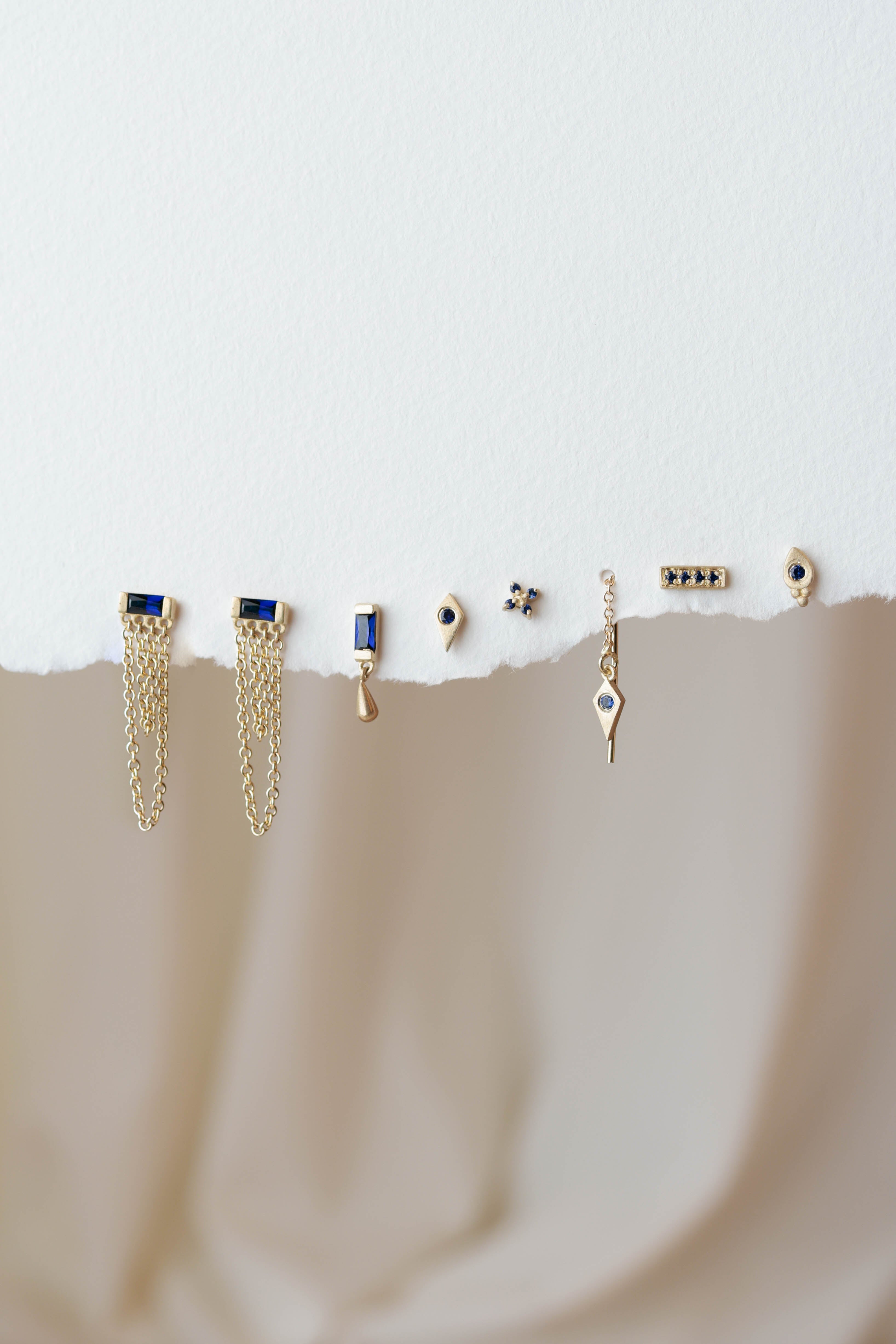 סט עגילי זהב עם אבני ספיר בגוונים כחולים, שילוב עדין ומודרני שמאפשר יצירת מראה אישי, קליל ואלגנטי לכל יום או ערב