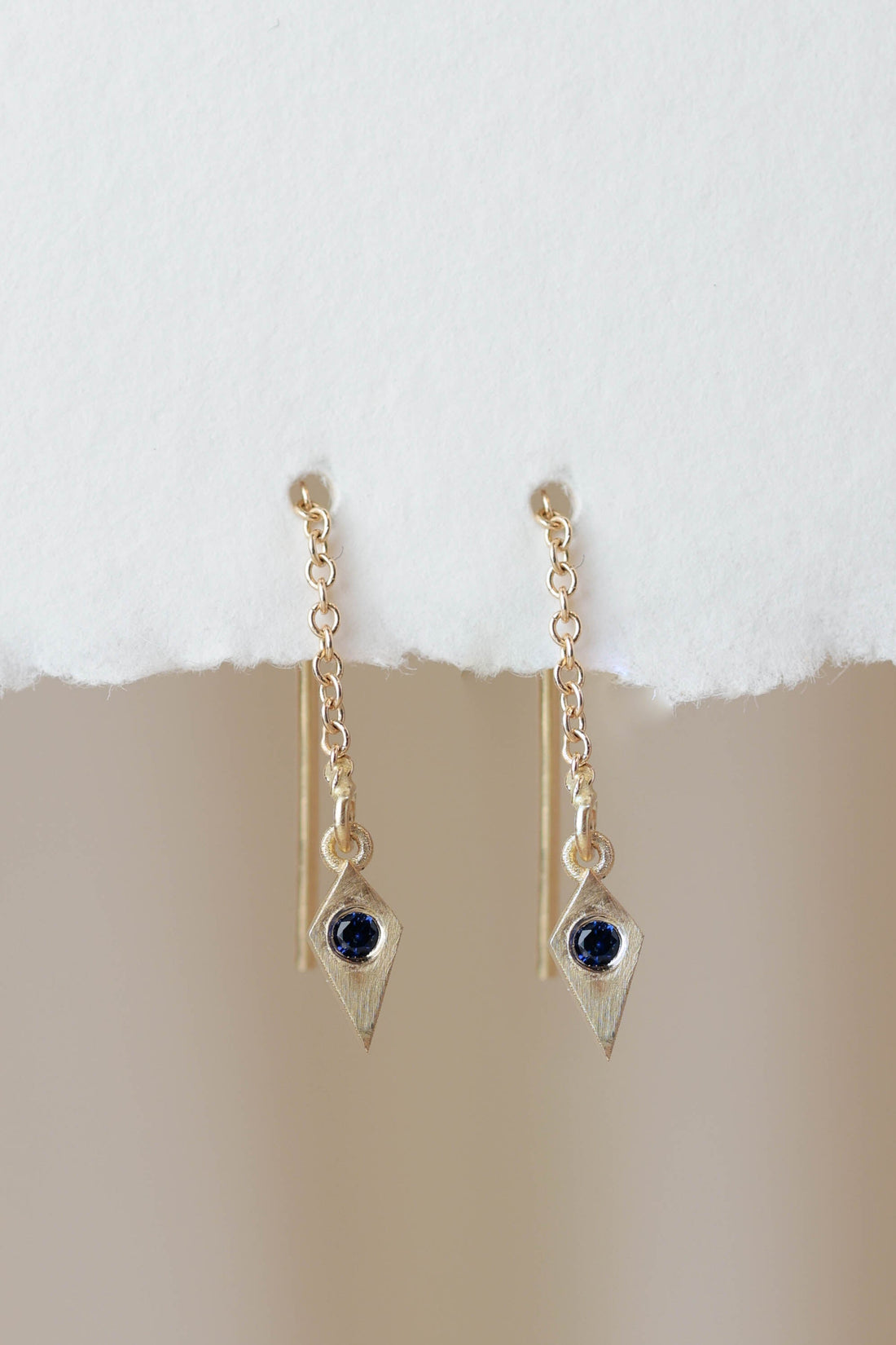 עגיל אוריה זהב בצורת מעוין עם חוט עדין שנופל ליצירת מראה מינימליסטי ואלגנטי