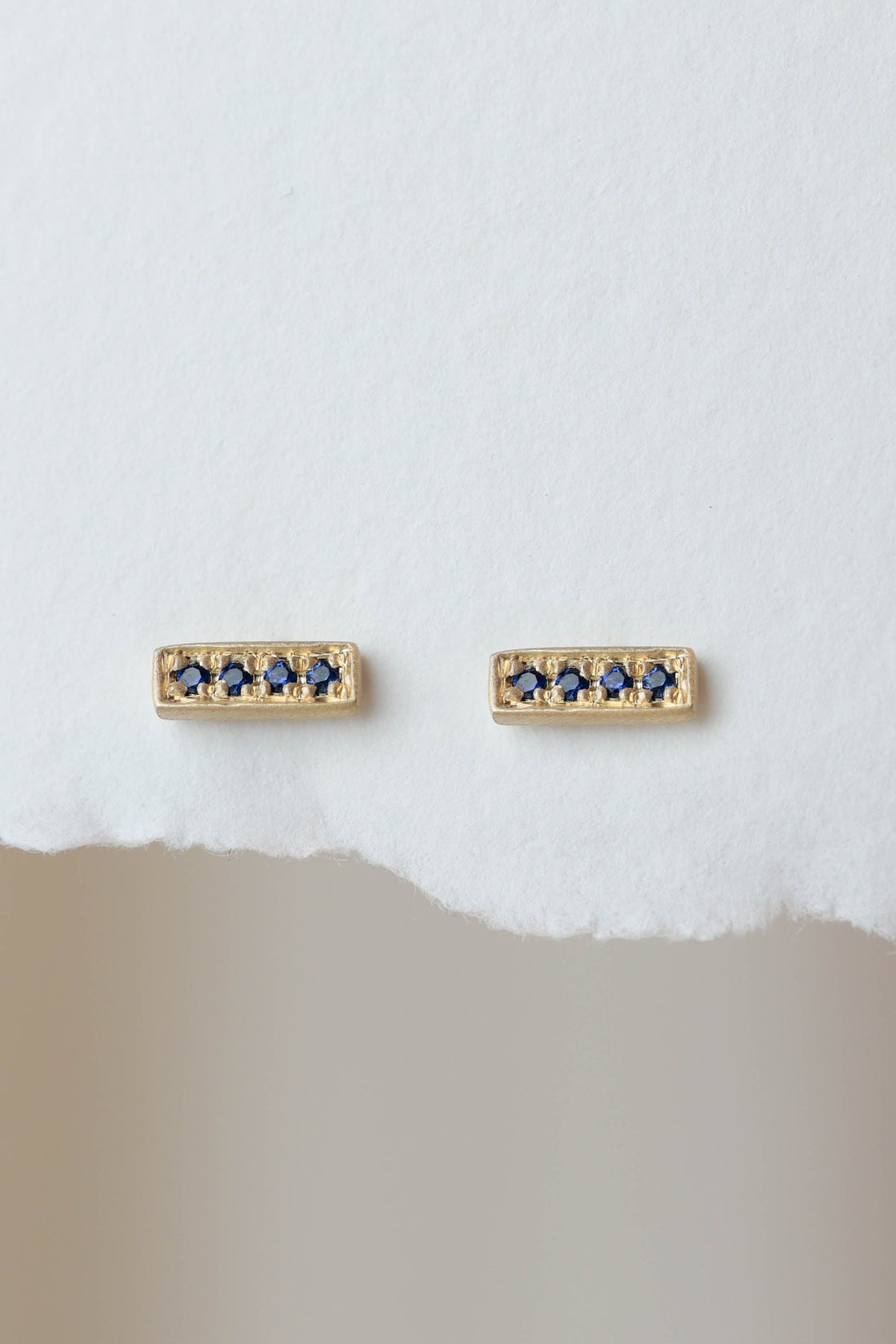 עגיל זהב בצורת מלבן עם ארבע אבני ספיר עיגוליות ליצירת מראה מינימליסטי ואלגנטי