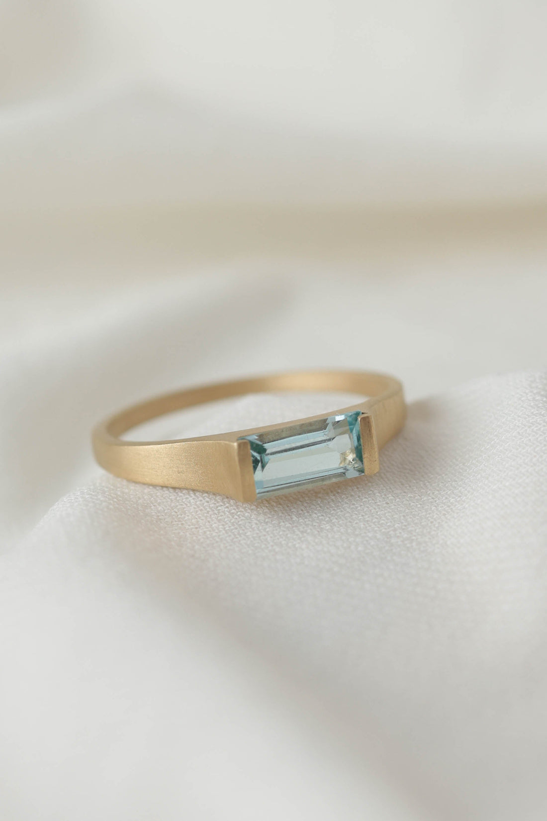 טבעת זהב מוברשת עם אבן טופז סקיי בגוון כחול בהיר.