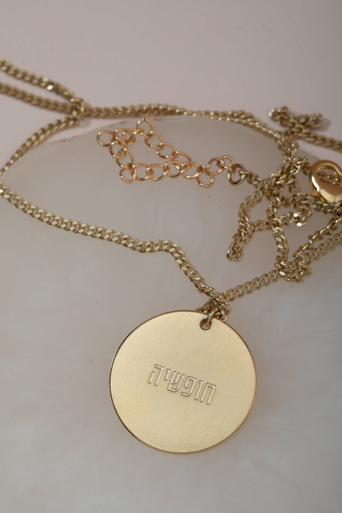 שרשרת אמיתה בצבע טורקיז מבית הדס קוקה תכשיטים, עיצוב נקי עם חריטה של מילה, מונחת על רקע לבן